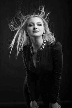 Mükemmel makyajlı ve rüzgarda saçı olan zarif sarışın kadın stüdyoda poz veren bir bluz giyiyor. Siyah ve beyaz çekim