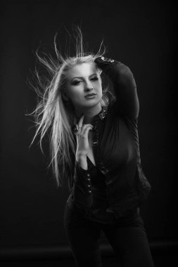 Harika makyajlı ve rüzgarda saçı olan sarışın kadın stüdyoda poz veren bir bluz giyiyor. Siyah ve beyaz çekim