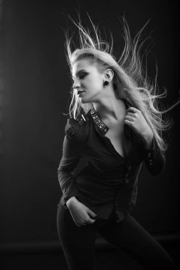 Mükemmel makyajlı, uzun dalgalı saçlı, şık sarışın kadın bluz giyer, stüdyoda poz verir. Siyah ve beyaz çekim