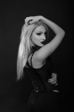 Parlak makyajlı ve uzun sarı saçlı seksi genç manken dantelli korse giyer. Siyah beyaz stüdyo çekimi