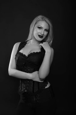 Parlak makyajlı ve uzun sarı saçlı neşeli genç manken dantelli korse giyer. Siyah beyaz stüdyo çekimi