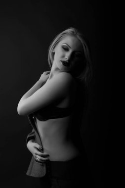 İnanılmaz genç bayan karanlık stüdyoda sütyen giyiyor. Tek renkli çekim.