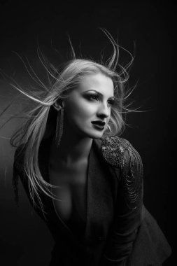 Parlak makyajlı ve uzun dalgalı saçlı çekici genç manken ceket giyiyor. Siyah beyaz stüdyo çekimi