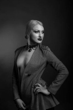 Parlak makyajlı muhteşem bir kadının siyah beyaz stüdyo portresi çıplak bir vücutta ceket giyer.