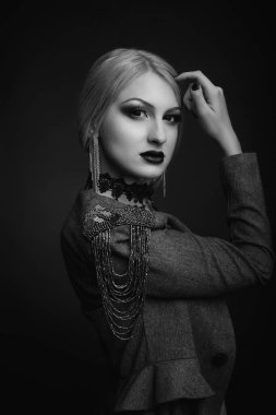 Parlak makyajlı güzel bir kadının siyah-beyaz stüdyo portresi çıplak bir vücutta ceket giyer.