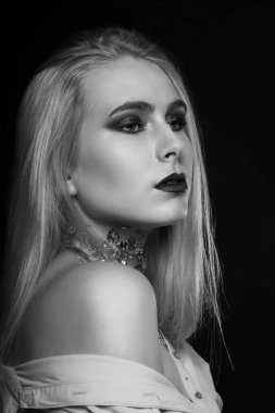 Siyah-beyaz güzellik çekimi: boynundaki parlak makyaj ve folyoyla stüdyoda poz veren güzel sarışın model.