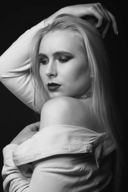 Stüdyoda boynundaki folyo ve parlak makyajla poz veren inanılmaz sarışın manken. Tek renkli çekim.