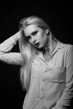 Stüdyoda boynundaki parlak makyaj ve folyoyla poz veren muhteşem sarışın manken. Tek renkli çekim.