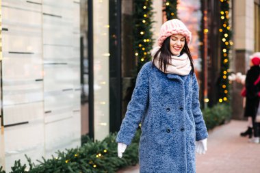 Çekici esmer kadın, şehirde çelenklerle süslenmiş açık pembe bir şapka ve eşarp takıyor. Metin için boşluk