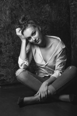 Doğal makyajlı şık genç bir kadın stüdyo da gömlek ve kot pantolon giyer. Siyah beyaz portre