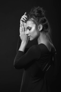 Rüya gören genç bir kadının dramatik portresi karanlık bir odada siyah bir elbise giyiyor. Siyah beyaz portre