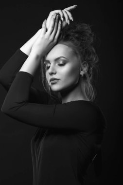 Sorunlu genç bir kadının dramatik portresi karanlık bir odada siyah bir elbise giyiyor. Siyah beyaz portre