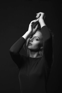 Hassas bir genç kadının dramatik portresi karanlık bir odada siyah bir elbise giyiyor. Siyah beyaz portre