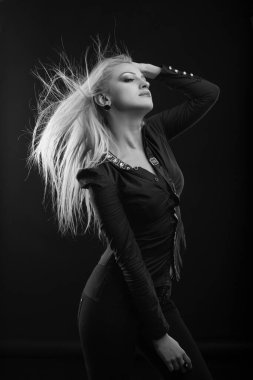 Mükemmel makyajlı, uzun dalgalı saçlı, gösterişli sarışın kadın stüdyoda poz veren bir bluz giyiyor. Siyah ve beyaz çekim