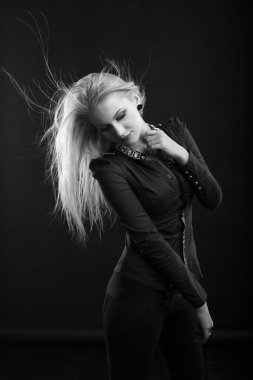 Mükemmel makyajlı ve rüzgarda saçı olan çekici sarışın kadın stüdyoda poz veren bir bluz giyiyor. Siyah ve beyaz çekim