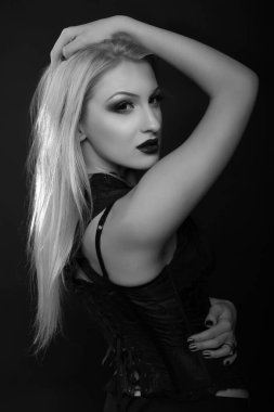 Parlak makyajlı ve uzun sarı saçlı sevimli genç manken dantelli korse giyer. Siyah beyaz stüdyo çekimi