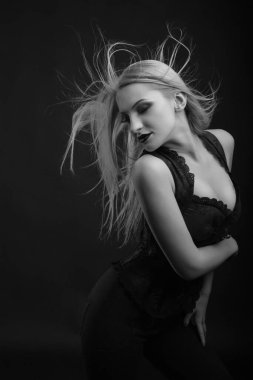 Parlak makyajlı ve uzun dalgalı saçlı muhteşem genç manken dantelli korse giyer. Siyah beyaz stüdyo çekimi