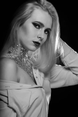 Siyah-beyaz güzellik çekimi: Stüdyoda parlak makyaj ve folyoyla poz veren yumuşak sarışın model.