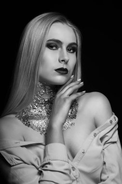Siyah-beyaz güzellik çekimi: Stüdyoda parlak makyaj ve folyoyla poz veren muhteşem sarışın model.