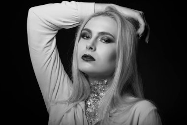 Parlak makyajlı ve folyoyla stüdyoda poz veren muhteşem sarışın bir model. Tek renkli çekim.