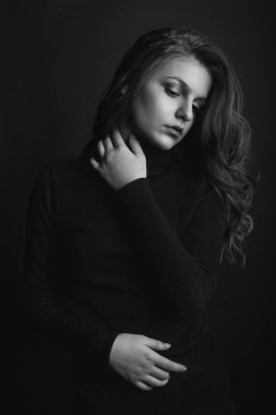 Kıvırcık uzun saçlı zarif kadın siyah balıkçı yaka giyiyor. Stüdyo çekimi. Siyah ve beyaz renkler