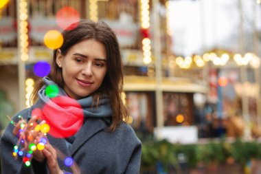 Memnun kadın bokeh ışığıyla sokakta yürürken gri bir ceket giyiyor. Boş boşluk