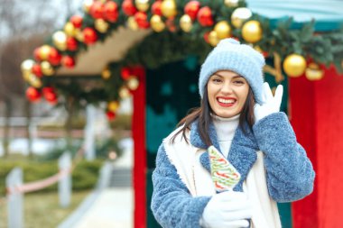 Noel pazarında elinde şeker tutan muhteşem gülümseyen kadın. Özelleştirme alanı