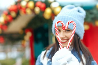 Kalp şeklinde şeker tutan neşeli esmer bir kadın. Metin için boşluk