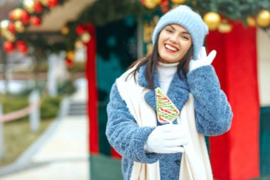 Noel pazarında elinde şeker tutan güzel, gülümseyen kadın. Özelleştirme alanı