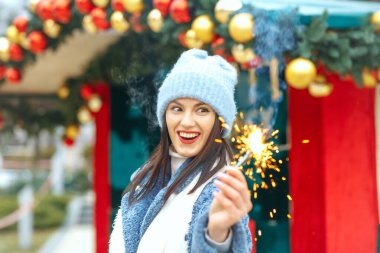 Heyecanlı genç kadın mavi ceket giyiyor Bengal ışıklarıyla tatilin tadını çıkarıyor