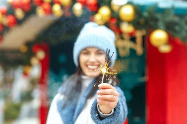 Mutlu genç kadın mavi ceket giyiyor Bengal ışıklarıyla tatilin tadını çıkarıyor
