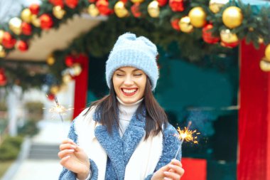 Havalı genç kadın mavi ceket giyiyor Bengal ışıklarıyla tatilin tadını çıkarıyor