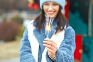 Mutlu genç kadın mavi ceket giyiyor Bengal ışıklarıyla tatilin tadını çıkarıyor