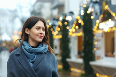 Kış aylarında şık giyinmiş şık genç bir kadın sokakta yürüyor. Boş boşluk