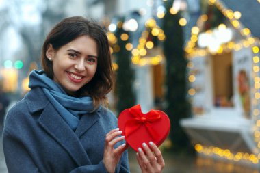 Neşeli esmer kadın Noel ağacının yanında hediye kutusu tutuyor. Metin için boşluk
