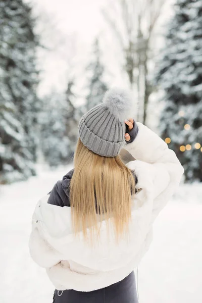 美しいですブロンド女性で白いコート見ますザ冬の森 — ストック写真