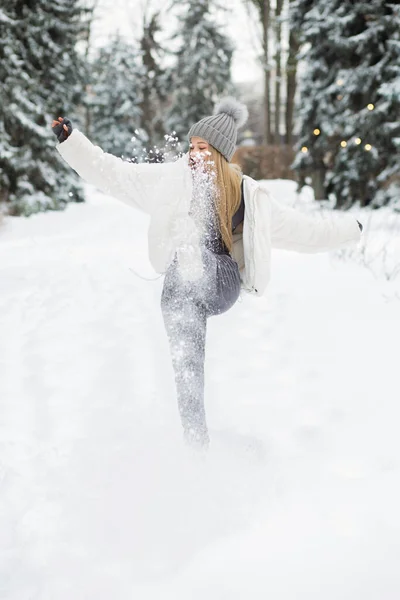 美しいですブロンド女性遊びます雪で森の中 — ストック写真