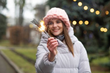 Göz kamaştırıcı gülümseyen kadın yeni yıl ağacının yanında maytaplarla eğleniyor.