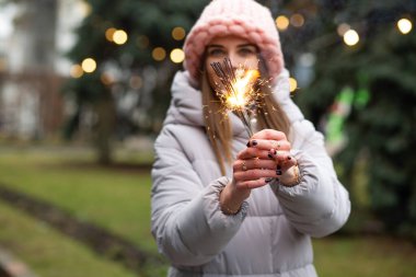 Olumlu gülümseyen kadın yeni yıl ağacının yanında maytaplarla eğleniyor.
