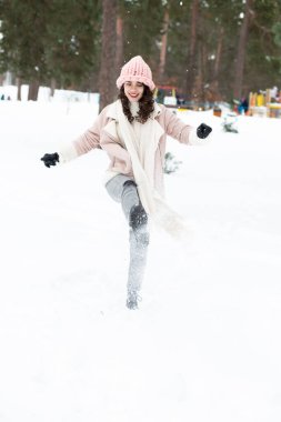 Neşeli esmer kadın ormanda karla oynuyor.