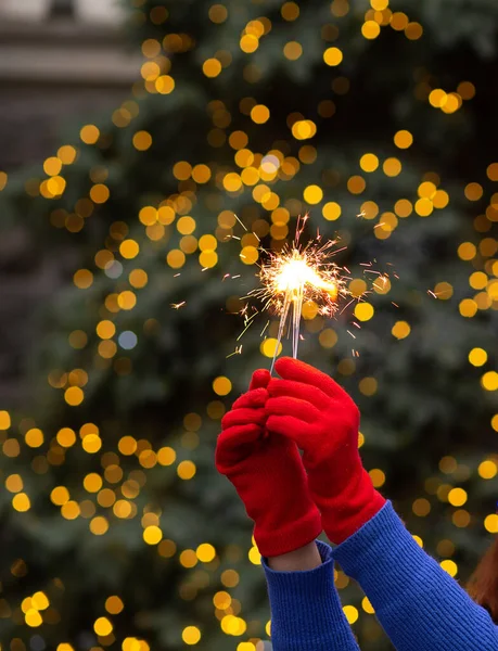 Woman hands holding sparkling lights at the street