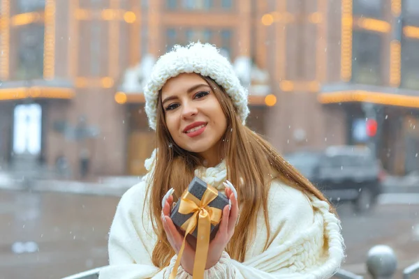 雪の中通りにギフトボックスを保持白いコートの愛らしいブロンドの女性 テキストのスペース — ストック写真