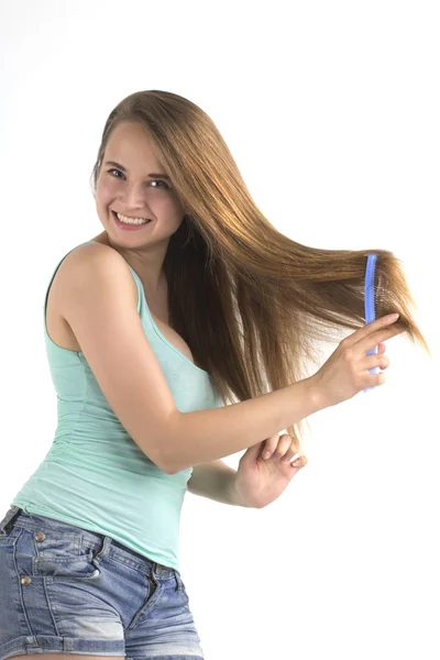 Jonge lachende vrouw haar haren borstelen — Stockfoto