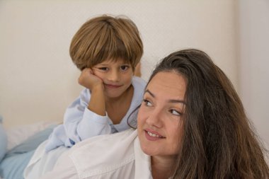 Anne ve çocuklar yatakta fotoğraf için kameraya bakıyorlar. Aile Yaşam Tarzı