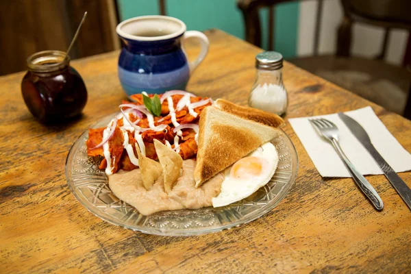 Delicioso desayuno mexicano de frijoles, chilaquiles y huevo frito —  Fotos de Stock