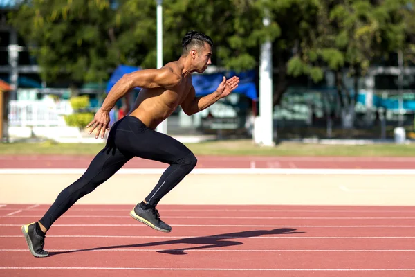 Jovem muscular homem pronto para iniciar uma pista atender . — Fotografia de Stock