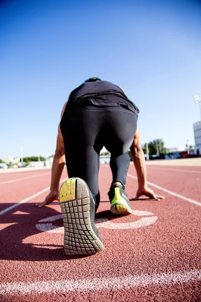 Ung muskulös man redo att börja en track meet. — Stockfoto