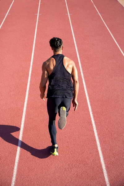 Jovem muscular homem pronto para iniciar uma pista atender . — Fotografia de Stock