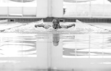 Kelebek yüzme tekniği olan genç bir atletik..
