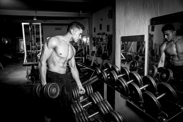 Giovane uomo che esercita in palestra scuro e vecchio — Foto Stock